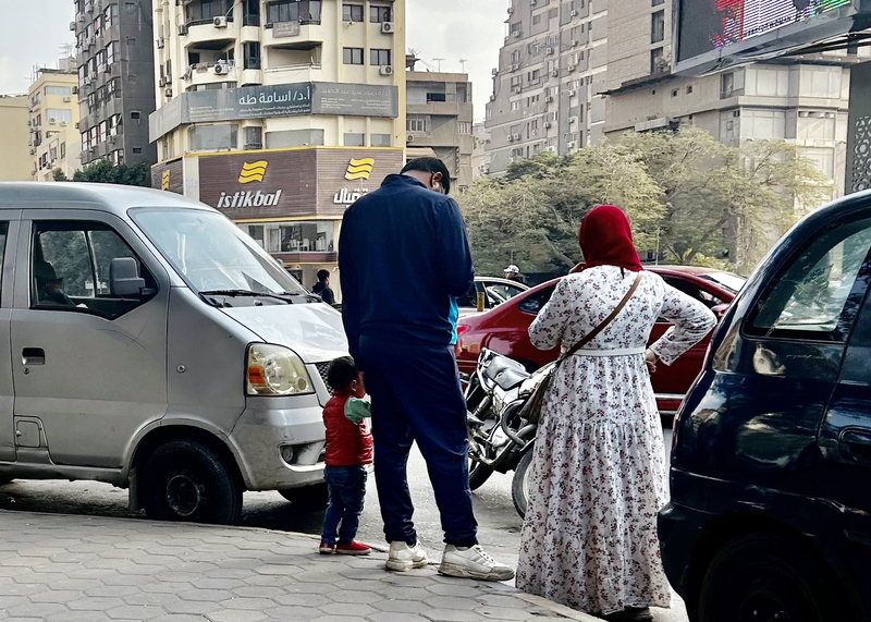 年輕埃及夫妻手牽幼兒站在開羅街頭